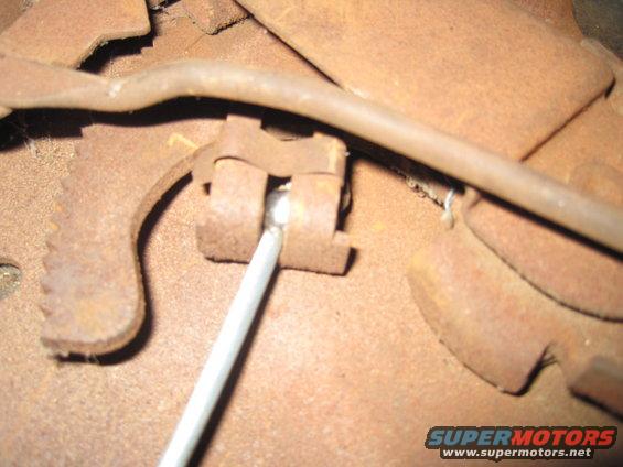 Close-up of a rusted brake mechanism with a metal rod inserted