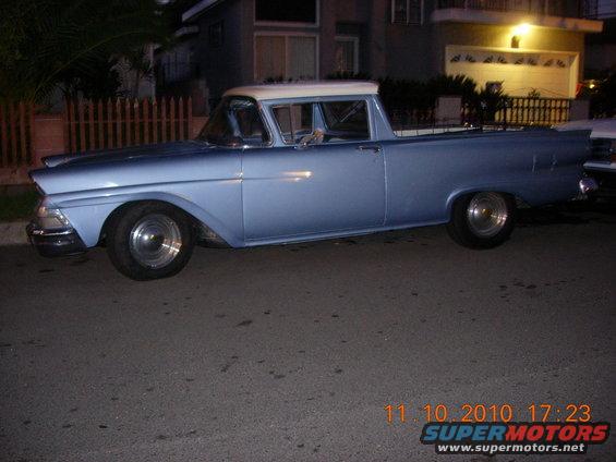 Light blue 1957 Ford Ranchero parked on a street at night