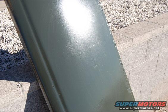 Green car door panel leaning against a block wall