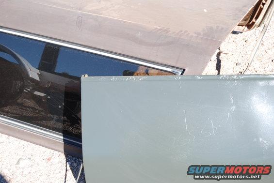 close-up of a car door and hood, showing some scratches on the door