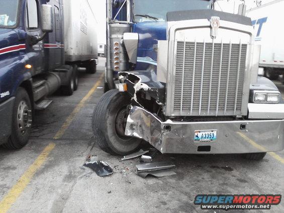 Blue 2009 Kenworth T800 semi-truck with a crumpled front bumper and fender, license plate A3353