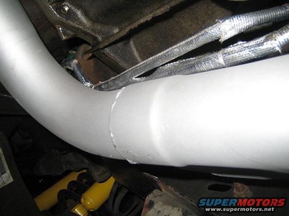 Exhaust pipe with a seam, yellow shock absorber, and engine block