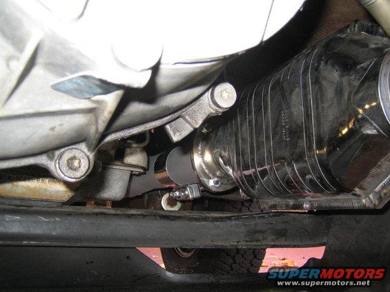 Close-up of a shiny, ribbed exhaust component attached to a vehicle's undercarriage