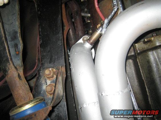 Exhaust pipe with an oxygen sensor attached, showing rusty metal brackets and bolts