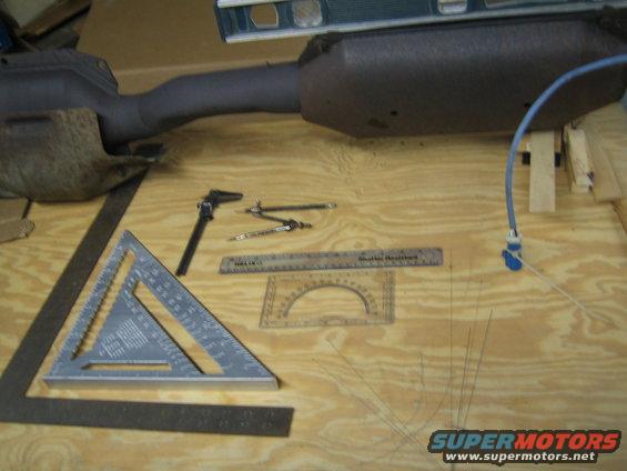 Exhaust pipe section with calipers, rulers, and a protractor on a wooden surface