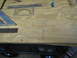 1996 Ford Bronco - Various drawing and measuring tools are laid out on a plywood surface, with pencil lines indicating a design or layout.