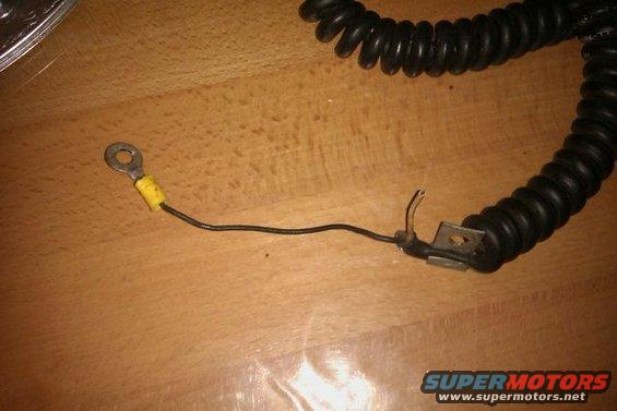 Black coiled electrical cord with a ring terminal and yellow insulation