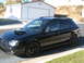 2005 Subaru Impreza - Black 2005 Subaru Impreza wagon with aftermarket wheels and roof rack.