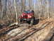 1991 Ford Bronco - Red Jeep Wrangler TJ climbs over rocks on a wooded trail.