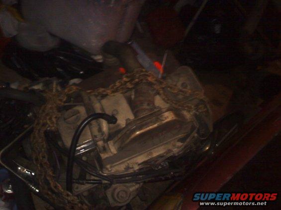 engine block with chain wrapped around it, in a cluttered space