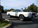 1973 Ford Ranchero - A white Ford Ranchero with a black accent on the hood is parked in an outdoor lot under a partly cloudy sky.