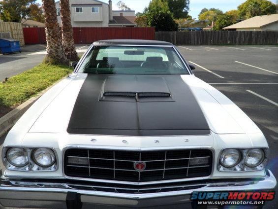 Front view of a white 1973 Ford Ranchero with a black hood stripe and scoop
