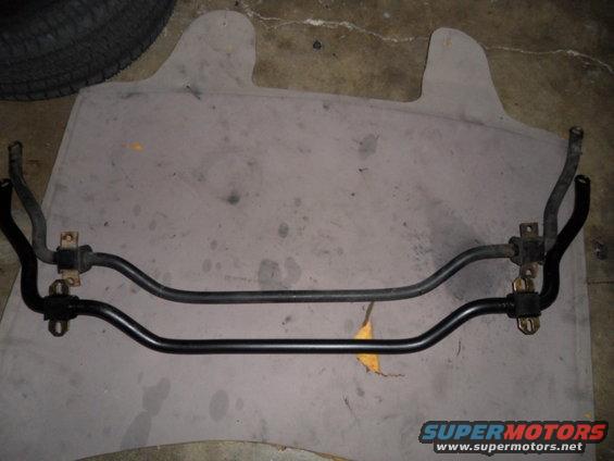 Two car sway bars laid out on a mat. One is lighter gray, the other is black