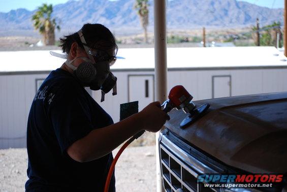 Person sanding hood of a 1980 Ford Bronco with a detail sander