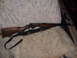1952 Matchless G80 - A rifle with a wooden stock and a black sling is laid out on a blanket.
