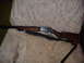 1952 Matchless G80 - A lever-action rifle with a wooden stock and blued metal receiver is visible on a patterned chair.