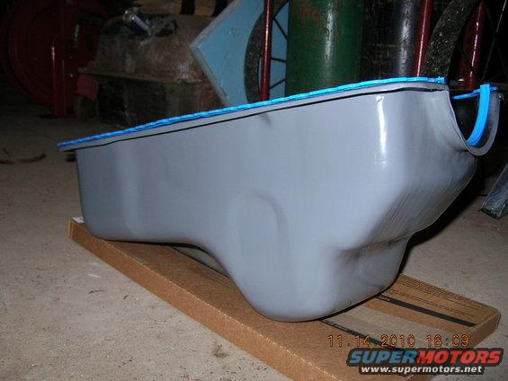 Gray oil pan with blue gasket on cardboard