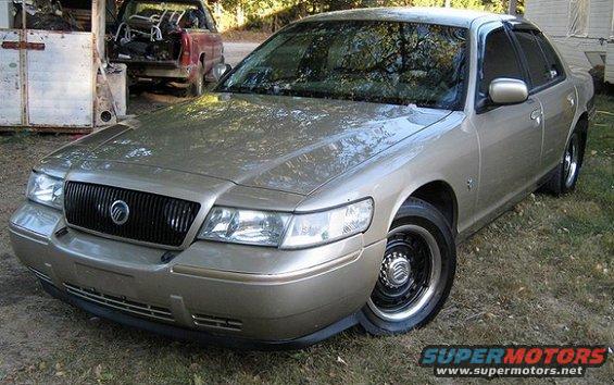 Gold 2000 Mercury Grand Marquis parked outside, red pickup truck in background