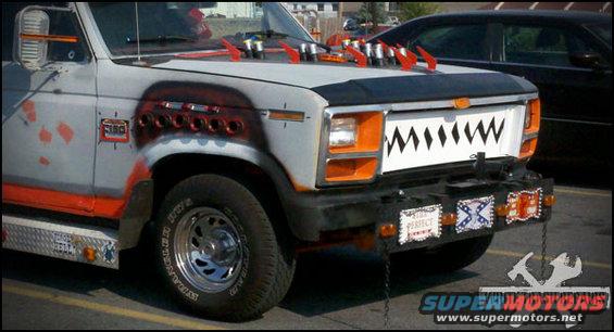 Modified pickup truck with shark teeth grille, red accents, and decorative plates on the bumper