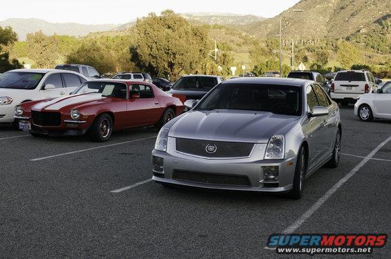 Silver 2006 Cadillac STS parked in a lot with a red Camaro behind it