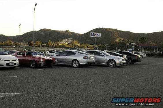Silver sedan parked in a lot, side and front visible, with a Mobil sign in the background