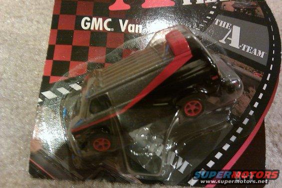 Black toy van with red trim and roof rack in blister packaging