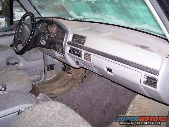 Interior view of a 1990s Ford F-Series truck or Bronco, showing the dashboard, steering wheel, and seats. XLT trim is visible