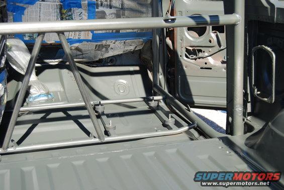 Interior of a vehicle with a roll cage installed. The door is open, revealing the door frame and some newspaper used for masking
