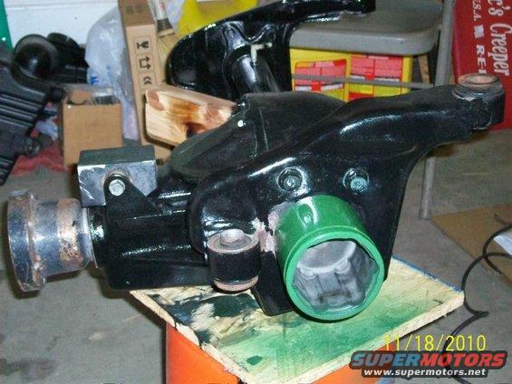 Black differential housing with green cap, on wooden board