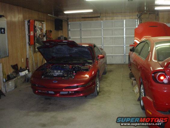 Red coupe with hood open in garage