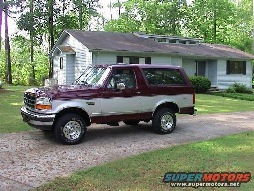 Maroon and silver 1996 Ford Bronco parked on a driveway in front of a house