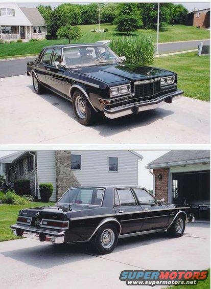 Black sedan parked in driveway, front 3/4 view
