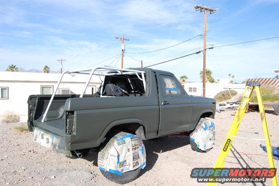 Ford Bronco with roll cage, wheels covered in newspaper, ready for paint