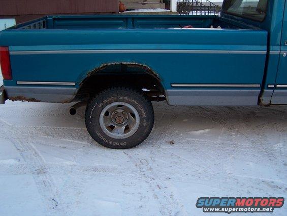 1994 Ford F-150 rear side view showing teal paint, rust on wheel arch, and grey lower trim