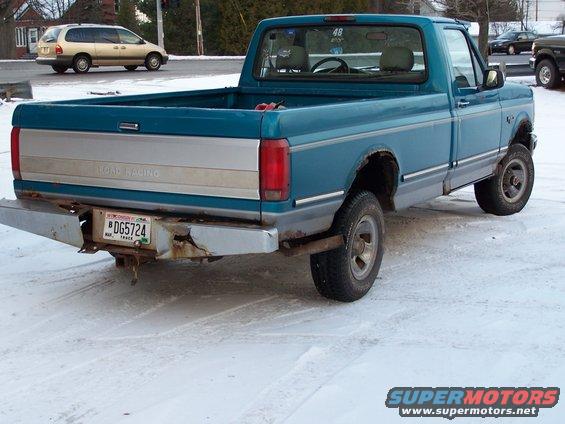 Rear view of a blue 1994 Ford F-150 pickup truck with a dented bumper and a Wisconsin license plate