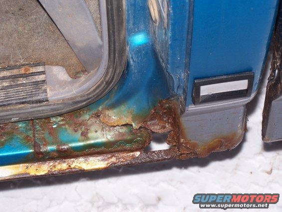 Blue truck door sill with extensive rust damage