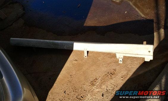 Car bumper trim piece, looks like a silver and white plastic strip with mounting brackets