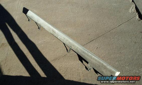 Silver car bumper with mounting brackets, lying on concrete