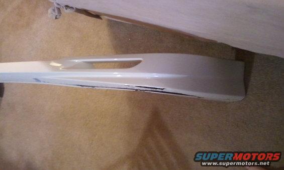 White car bumper with black scuff marks on the lower edge and a horizontal cutout