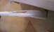 2003 Acura TL - A white car bumper with visible damage on its lower edge is shown from the side.