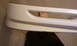 2003 Acura TL - A white car bumper is shown, with a person's feet visible through a large horizontal opening in the part.