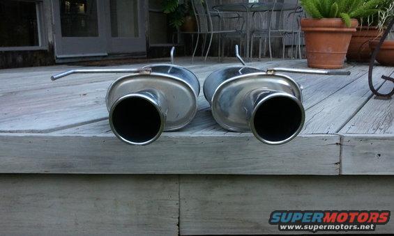 two exhaust mufflers sitting on a wooden deck