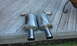 2003 Acura TL - Two chrome exhaust mufflers are shown resting on a weathered wooden deck.