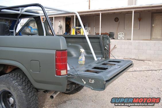 Gray Ford Bronco with tailgate down, roll cage, and spray bottle in bed