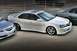 2003 Acura TL - A white 2003 Acura TL sedan is parked next to another vehicle, showing its front-right side and custom wheels.