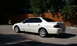 2003 Acura TL - A white 2003 Acura TL sedan is parked in front of a wooden fence on a sunny day.