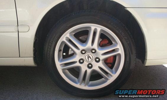 Front wheel of a 2003 Acura TL with Acura logo and red brake caliper