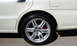 2003 Acura TL - Close-up of the rear wheel and fender of a white sedan, showing the tire and alloy rim.