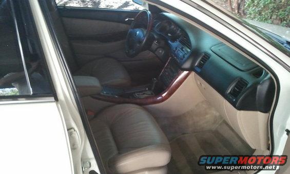 Interior shot of a car, showing leather seats, dashboard, and center console with wood trim