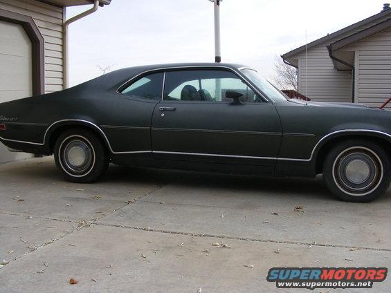 Side view of a dark coupe with chrome trim. Looks like a 1970 model